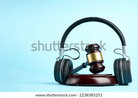Music copyright law concept. Headphones and judge gavel background with copy-space. Music piracy and owners rights