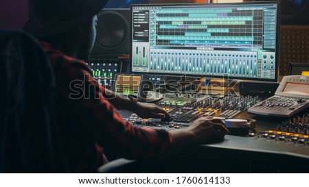 Music Creator, Musician, Artist Works in the Music Record Studio, Uses Surface Control Desk Equalizer Mixer. Buttons, Faders, Sliders to Broadcast, Record, Play Hit Song. Close-up Shot