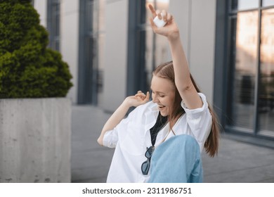 Music, dance and motivation with a business woman walking near office while feeling positive or carefree. Success, happy or smile with woman employee sitting near work in headphones with a smile. Win. - Shutterstock ID 2311986751
