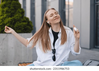Music, dance and motivation with a business woman walking near office while feeling positive or carefree. Success, happy or smile with woman employee sitting near work in headphones with a smile. Win. - Shutterstock ID 2311986753