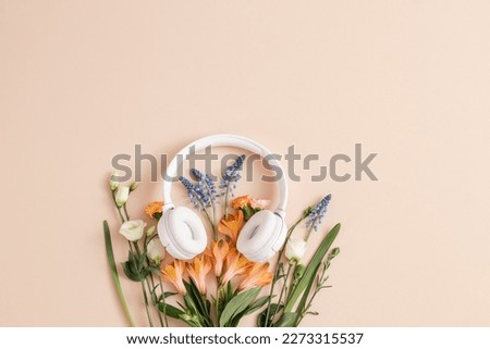 Music day concept.Stereo headphones with flowers on a pastel  background. Romantic music. Backdrop for music shop