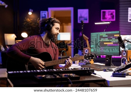 Music engineer playing new tunes on acoustic guitar and recording with daw software interface, preparing to do mixing and mastering session. Young songwriter creating soundtracks with instrument.