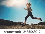 Music, exercise and woman running at park for healthy body, wellness or fitness workout. Earphones, cardio and trail runner training in nature for race, marathon and low angle outdoor with athlete