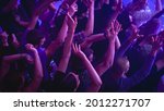 Music Festival Goers Party with Their Hands Up in the Air at a Concert in a Night Club. Shot from Above with Fans Cheering a Rock or Indie Band. Bright Colorful Strobing Lights Makes the Atmosphere