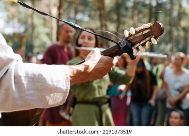 Music folk festival of the Middle Ages. Close-up of a musician playing the guitar outdoors, selective focus on the fretboard of the instrument. - Shutterstock ID 2191373519