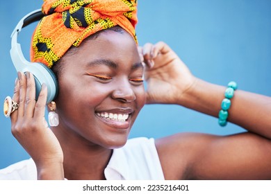Music, freedom and headphones with a black woman outdoor on a blue wall background enjoying a track. Radio, relax and happy with a young female streaming or listening to audio on a wireless headset - Shutterstock ID 2235216401