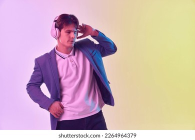 Music  Half  length portrait young man in headphones dancing isolated gradient yellow  purple background in neon light  Concept human emotions  youth culture  Copy space for ad 