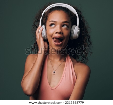 Music, headphones and gen z girl in studio for streaming, silly face or audio on green background. Podcast and goofy female model relax while listening to radio, audio or online playlist