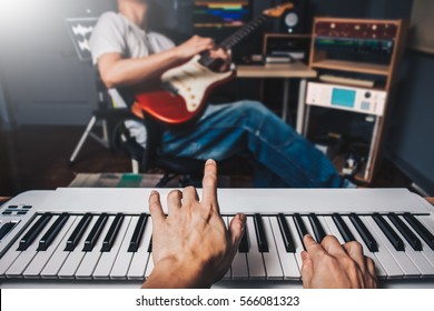 music jamming in sound studio, pianist hands playing keyboard on blurred guitar player background. film filter - Powered by Shutterstock