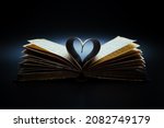 Music is the literature of the heart. It commences where speech ends. Opened antiquarian book with sheet music and pages curved into a heart shape.