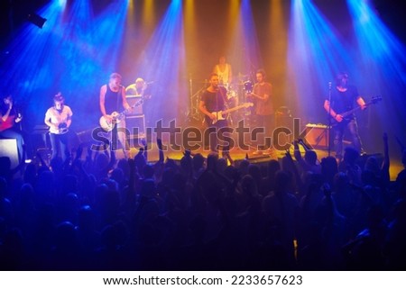 Music, live concert and band playing a song for audience at a rock, punk or folk festival. Disco light, night event and stage with performance artist play at a music festival with people cheering