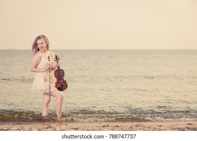 Music love, hobby and everyday passion concept. Woman on beach near sea holding violin playing in water - Shutterstock ID 788747737