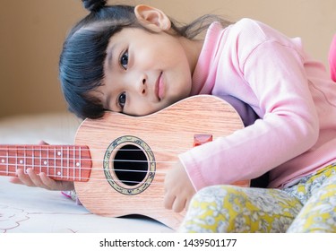 Music Lover Concept. Kid With Her Favorite Guitar Or Ukulele. The Dream Is To Be A Guitarist In Future.