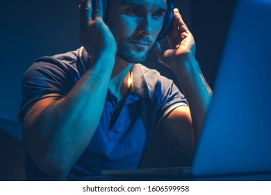 Music Mastering Job. Sound Technician Wearing Professional Headphones Listening and Editing Music Using Laptop Computer. 