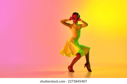 Music in movements  Emotional little girl in yellow stage dress dancing classical ballroom dance over gradient pink  yellow background in neon light filter  Concept beauty  professional dances