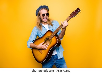 Music is my lifestyle! Excited and carefree musician dressed in casual clothes and spectacles playing the acoustic guitar and singing a song