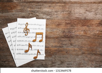 Music Notes With Sheets On Wooden Background, Flat Lay. Space For Text