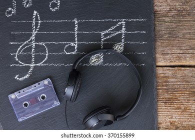Music notes and treble clef with old audio cassette and headphones 