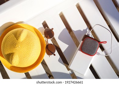 Music portable speaker is charged from the power bank via usb on a deck chair near the pool with beach accessories. Always in touch, travel gadgets, external battery for a smartphone. Copy space