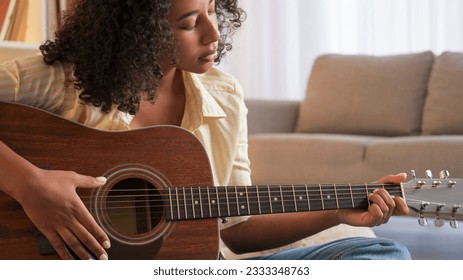 Music practice. Guitar leisure. Female player. Concentrated woman guitarist playing song on string acoustic instrument at home room. - Powered by Shutterstock