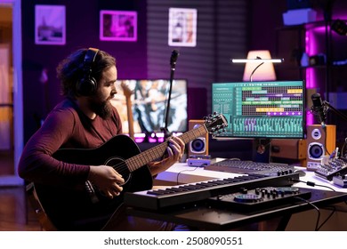 Music producer playing accords on acoustic instrument and recording tunes on daw software, prepares for mixing and mastering techniques. Young artist producing soundtracks with guitar. - Powered by Shutterstock