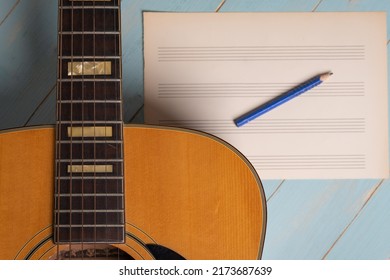 Music Recording Scene With Guitar, Empty Music Sheet And Pencil On Wooden Table