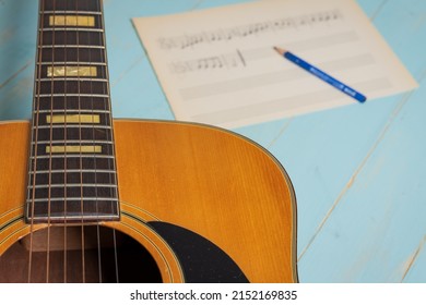 Music Recording Scene With Guitar, Music Sheet And Pencil On Wooden Table