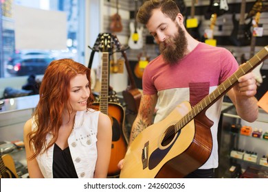 Music, Sale, People, Musical Instruments And Entertainment Concept - Happy Couple Of Musicians With Guitar At Music Store