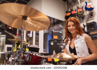 music, sale, people, musical instruments and entertainment concept - smiling female musician playing cymbals at music store - Powered by Shutterstock