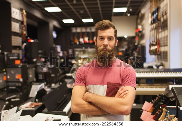 music,\
sale, people, musical instruments and entertainment concept - male\
assistant or customer with beard at music\
store