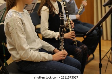 Music school students girls and boys playing clarinet sit in a row at an orchestra rehearsal.A high school female pupil holding a musical instrument in her hand close-up