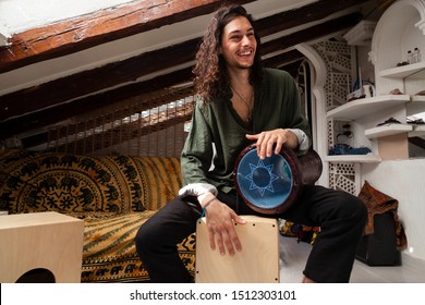 Music shot of a young handsome man playing cajon drum box and arabic darbuka at the same time on an alternative house studio background. Having fun experimenting with exotic instruments at home.
 - Powered by Shutterstock