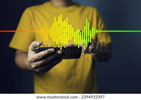 Music and sound wave concept with man in yellow t-shirt holding smartphone and playing music with frequency sound wave spectrum icon