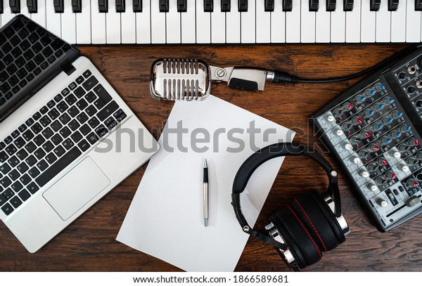 Music studio equipment and white paper with pen.\
Songwriting concept.