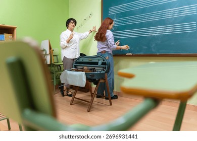Music teacher explaining notation and lines on a chalkboard to a female student during a violin lesson in a classroom