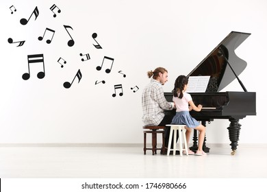 Music Teacher Giving Piano Lessons To Little Girl  