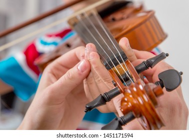 music teacher works with a child playing the violin.  Hands close up