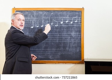 Music Teacher Writing On A Blackboard