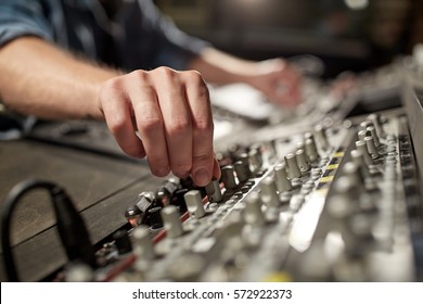 music, technology, people and equipment concept - man using mixing console in sound recording studio
