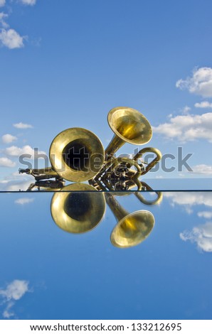 musical brass wind instruments on mirror and sky