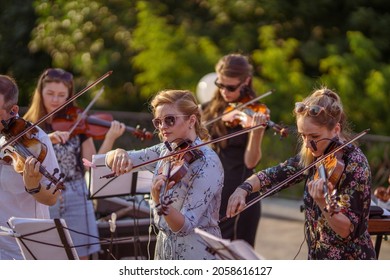 Musical ensemble playing violin at outdoor concert - Shutterstock ID 2058616127