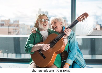 Musical holiday. Waist up portrait of amorous married man and woman enjoying playing on instrument