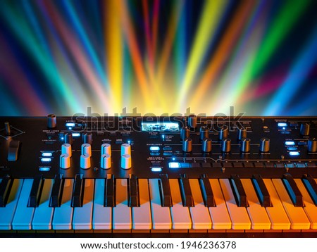 Musical instrument electronic synthesizer on a background of colored rays. Background on the theme of music, disco and synthesizer games.
