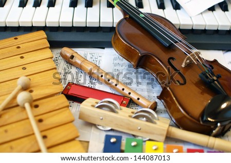 Musical instruments for children: xylophone, children's violin, tambourine, flute, harmonica, piano keyboard.