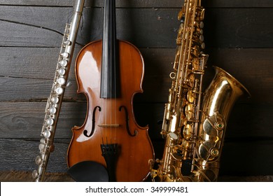 Musical Instruments: Saxophone, Violin And Flute On Wooden Background