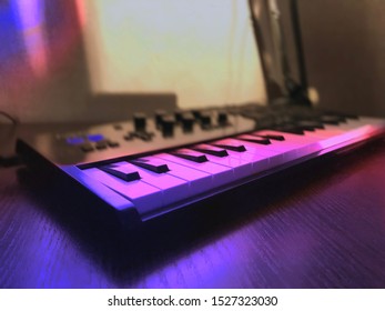 A Musical Keyboard Stands On A Table In Purple Light