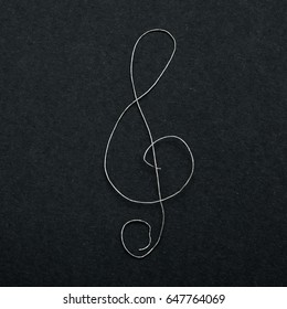 Musical Sign Clef Made Of Broken Guitar String On Black Paper