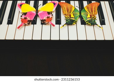 Musical synthesizer piano keys with colored butterflies. place for text                                - Shutterstock ID 2311236153