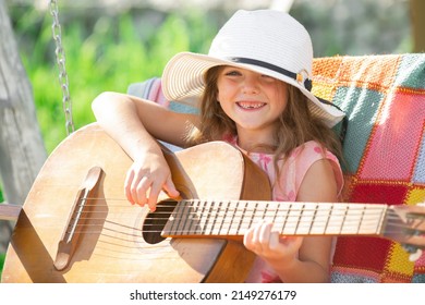 Musician Child Playing Guitar. Kid Girl Singing And Playing Guitar Outside. Kids Music And Songs. Smiling Child Playing Outdoors In Summer.