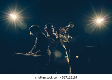 Musician Duo band playing a Trumpet and keyboard on black background with spot light and lens flare, musical concept - Powered by Shutterstock